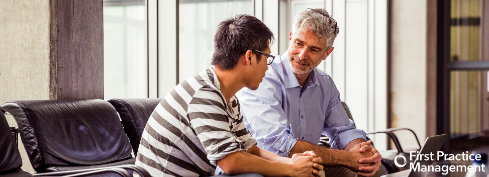 Two men talking 973x352